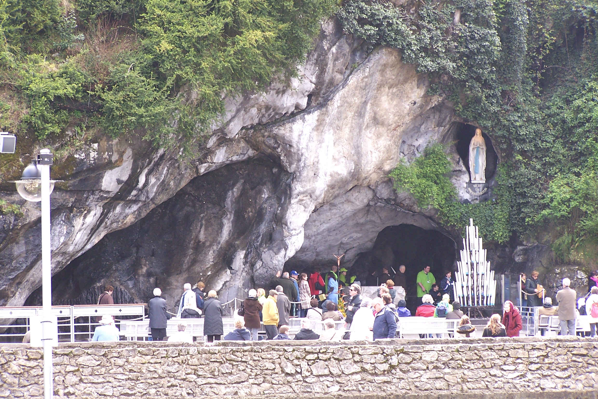 The grotto of Massabielle at Lourdes with candles, altar, and the statue of the Virgin in the rock niche